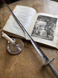 open book with candlestick and sword